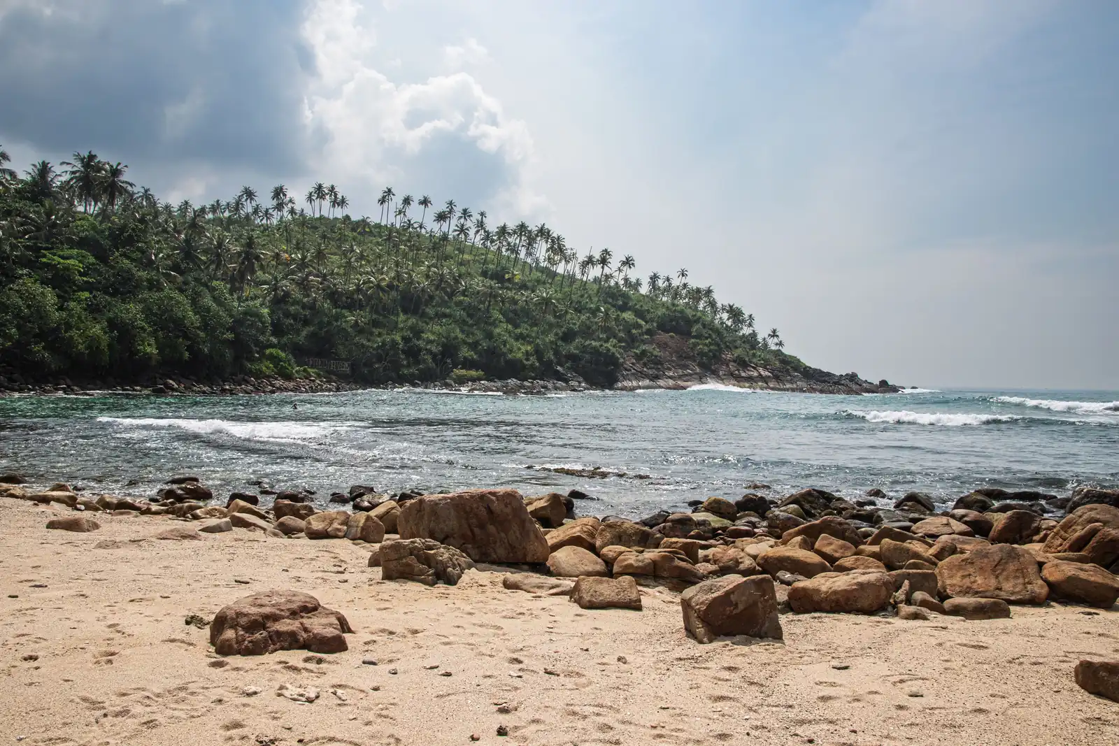 Rock boulders and a palm-covered headland at a cove near Mirissa, Sri Lanka in January
